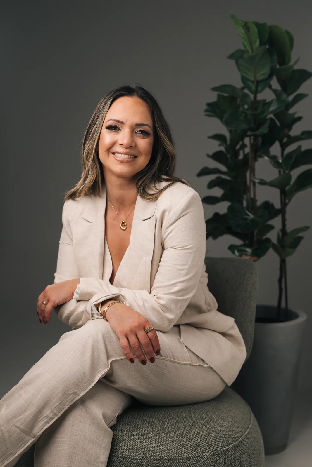 Camila Osório, cerimonialista, sentada numa poltrona verde, sorrindo