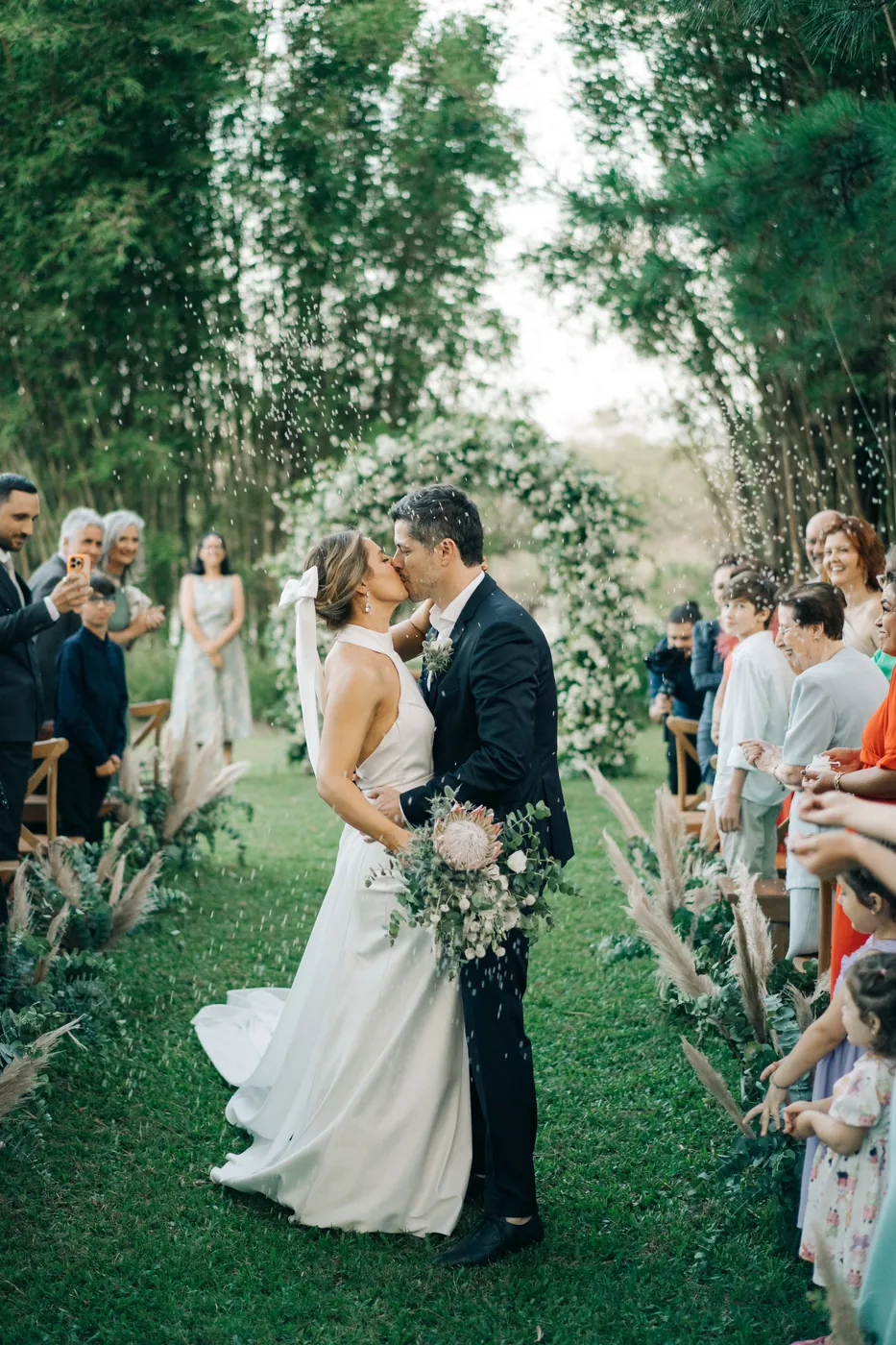 Casamento de Julia e Diego: noivos se beijando no corredor de grama